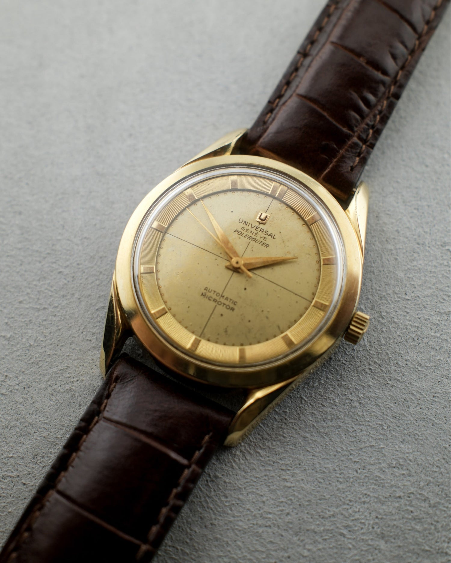 Vintage gold watch with brown leather strap on a gray background
