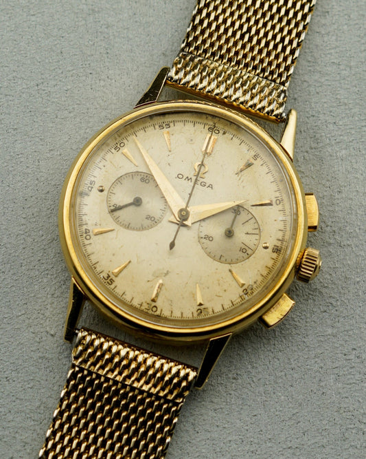 Vintage gold wristwatch with a detailed face on a gray background