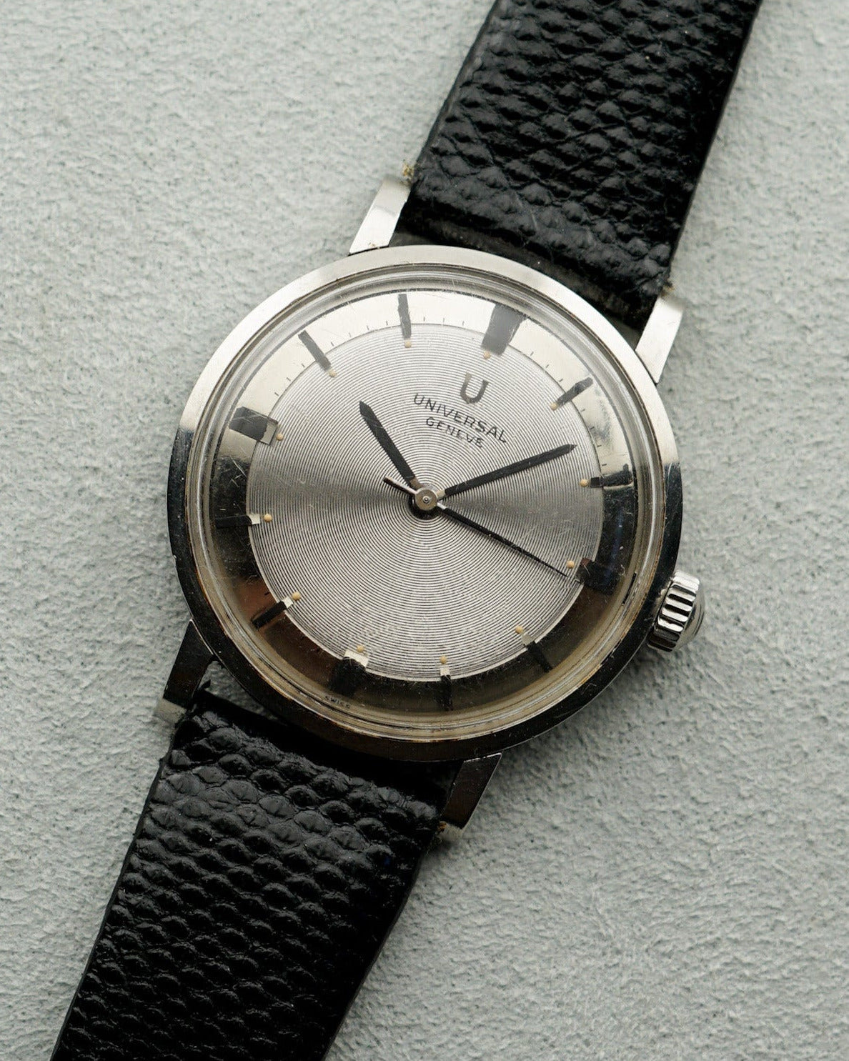 Vintage watch with black strap and silver case on a light gray background